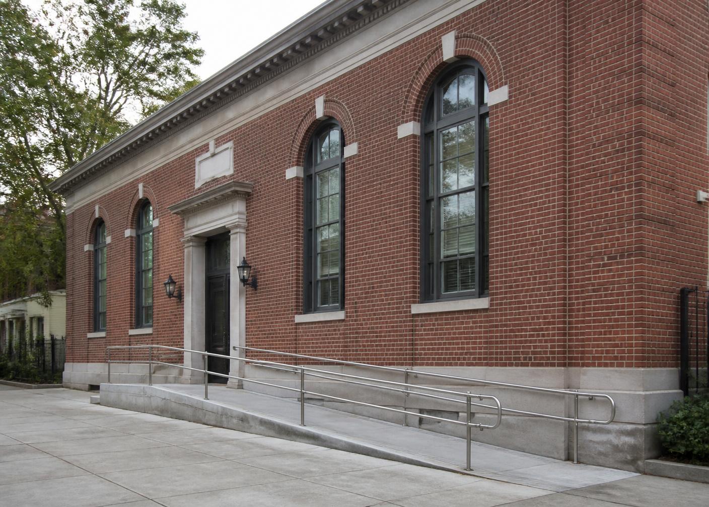 Brick civic building in Queens with arched windows and an accessible entrance ramp
